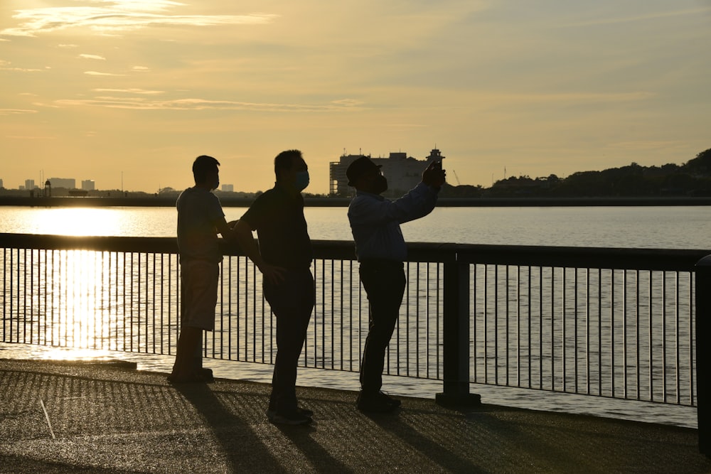 a couple of people standing next to a body of water