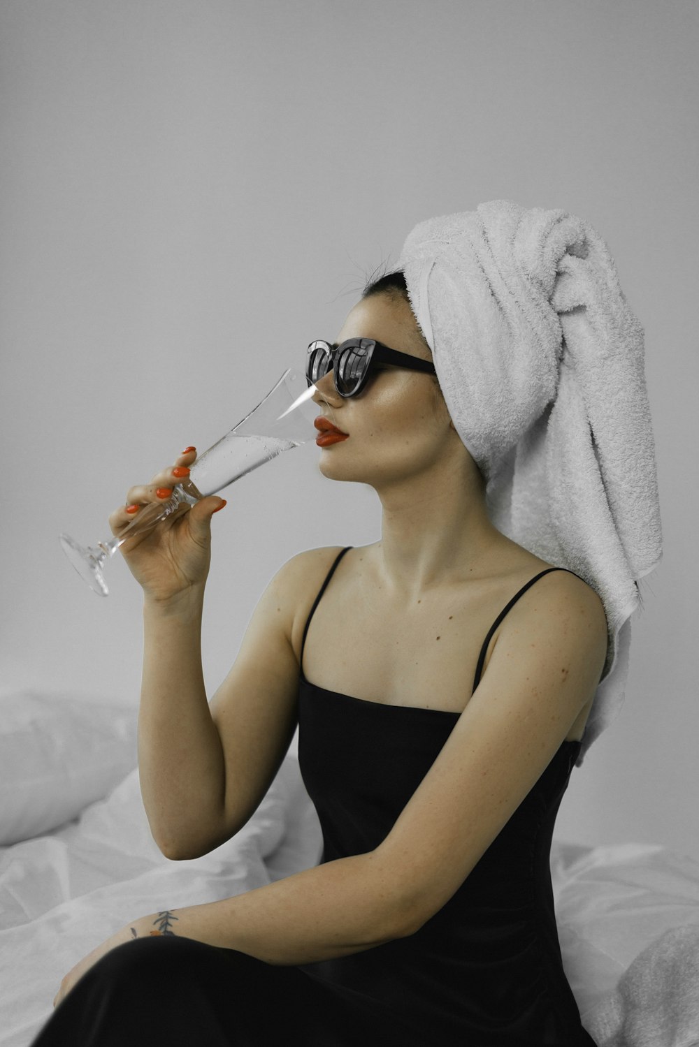 a woman with a towel on her head drinking a glass of wine