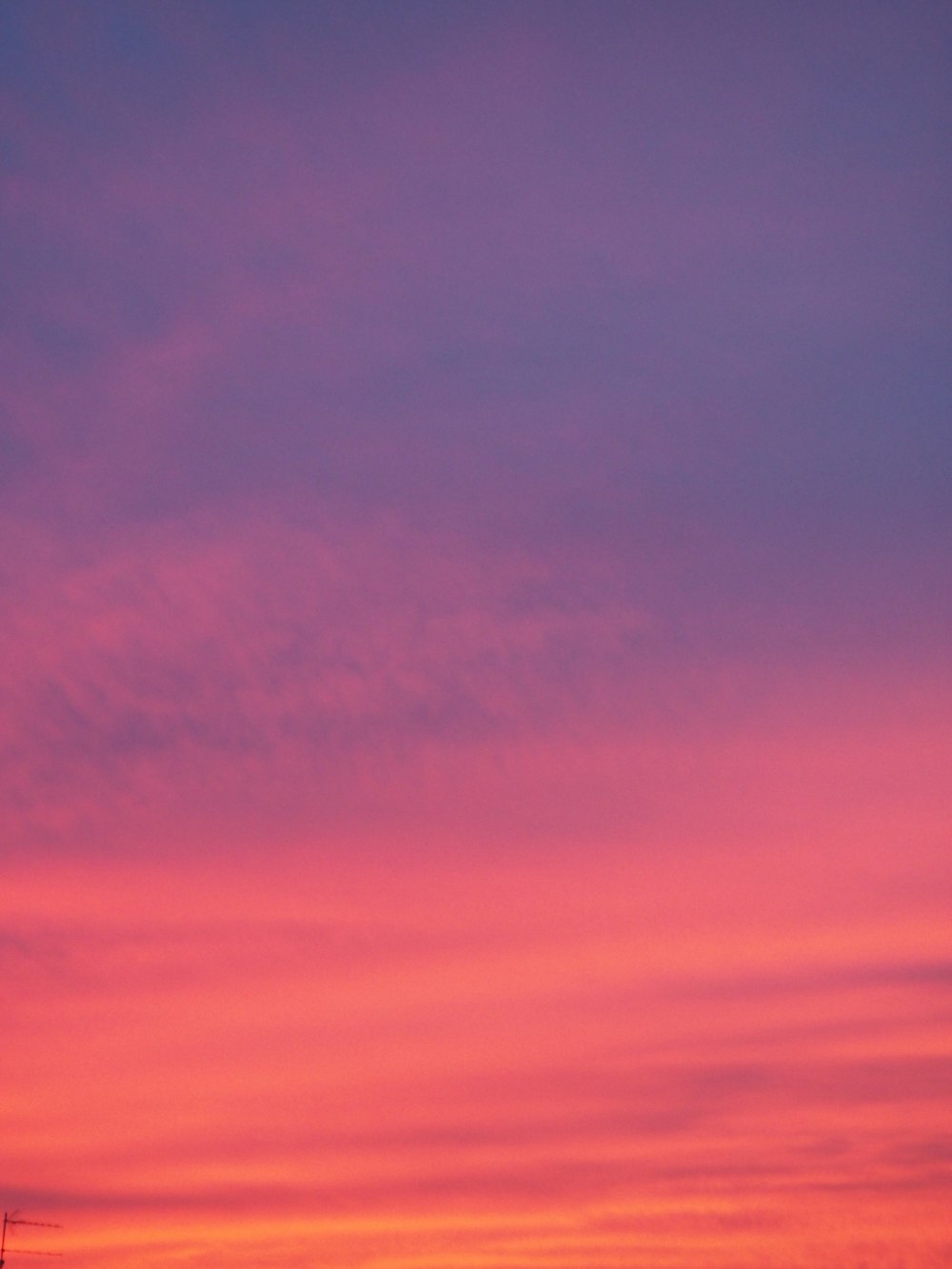 a plane flying in the sky at sunset