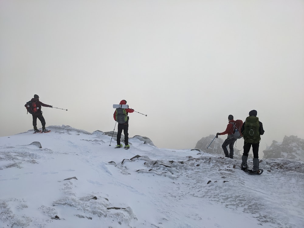 um grupo de pessoas em pé no topo de uma encosta coberta de neve