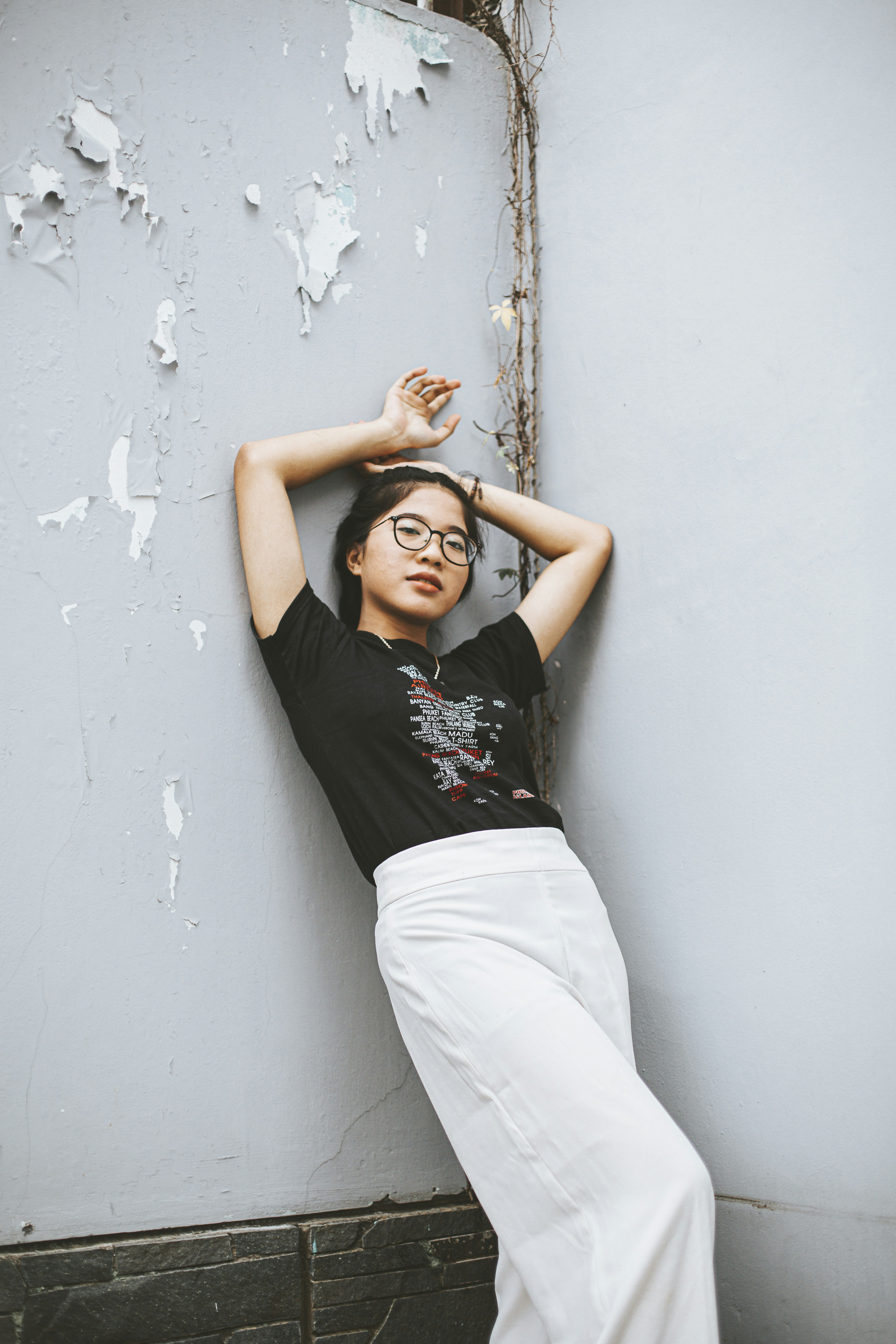 A woman leaning against a wall with her hands on her head photo – Free ...