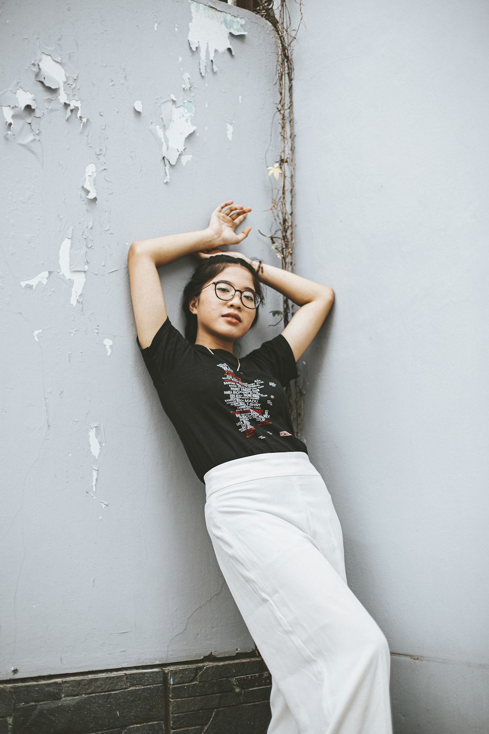 a woman leaning against a wall with her hands on her head