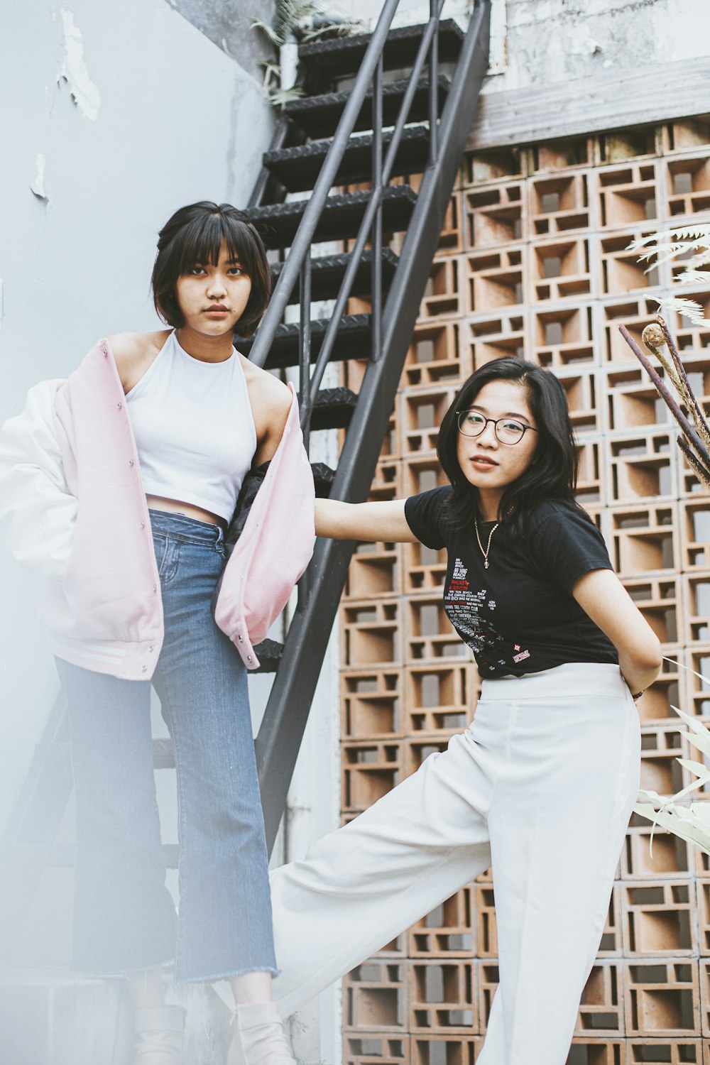 two women standing next to each other near a stair case