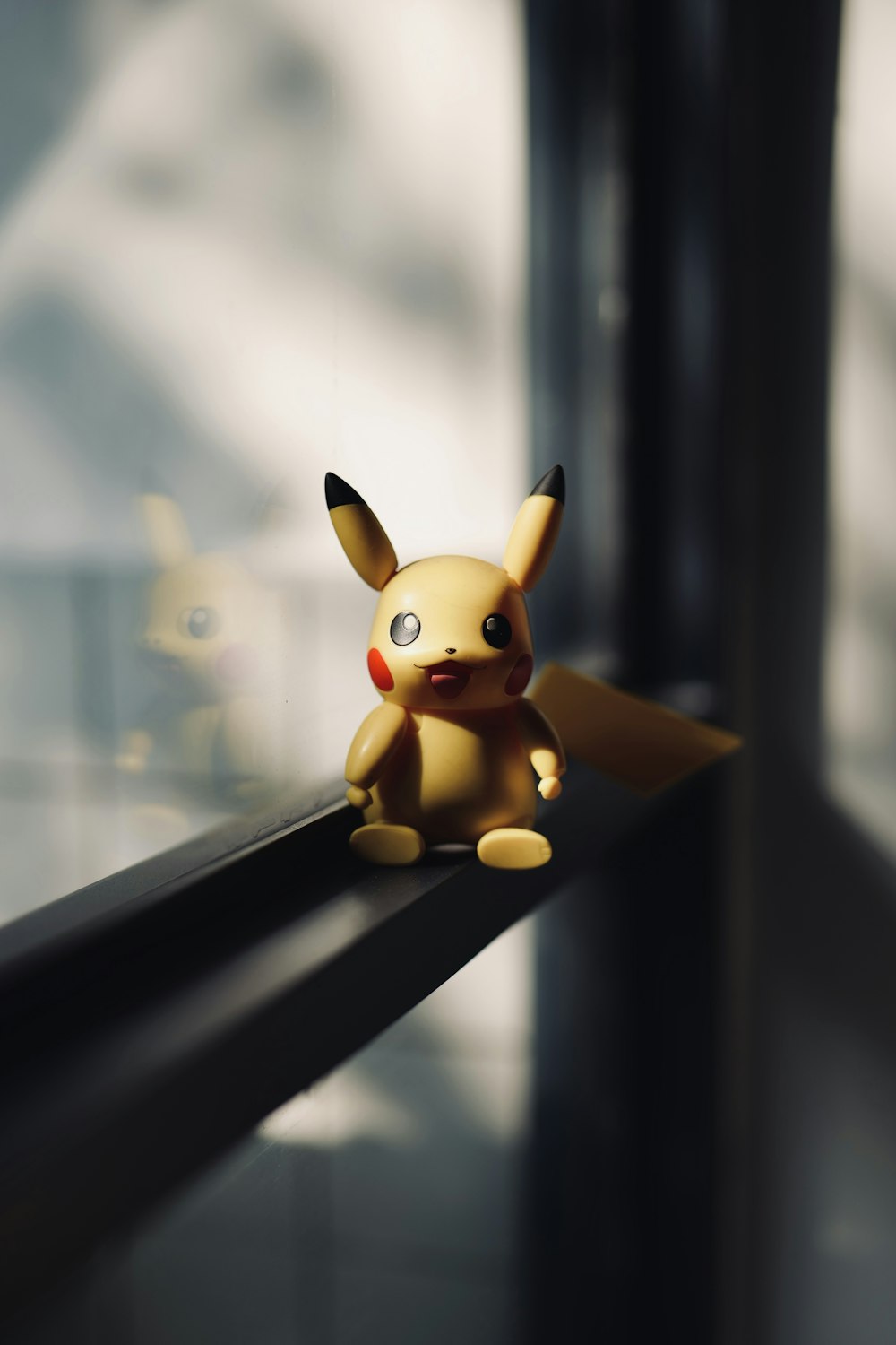 a toy pikachu sitting on a window sill
