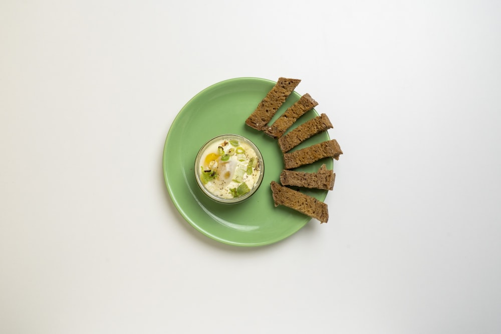 a green plate topped with crackers and a bowl of dip