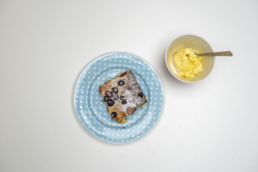 a blue plate with a piece of cake and a bowl of yogurt