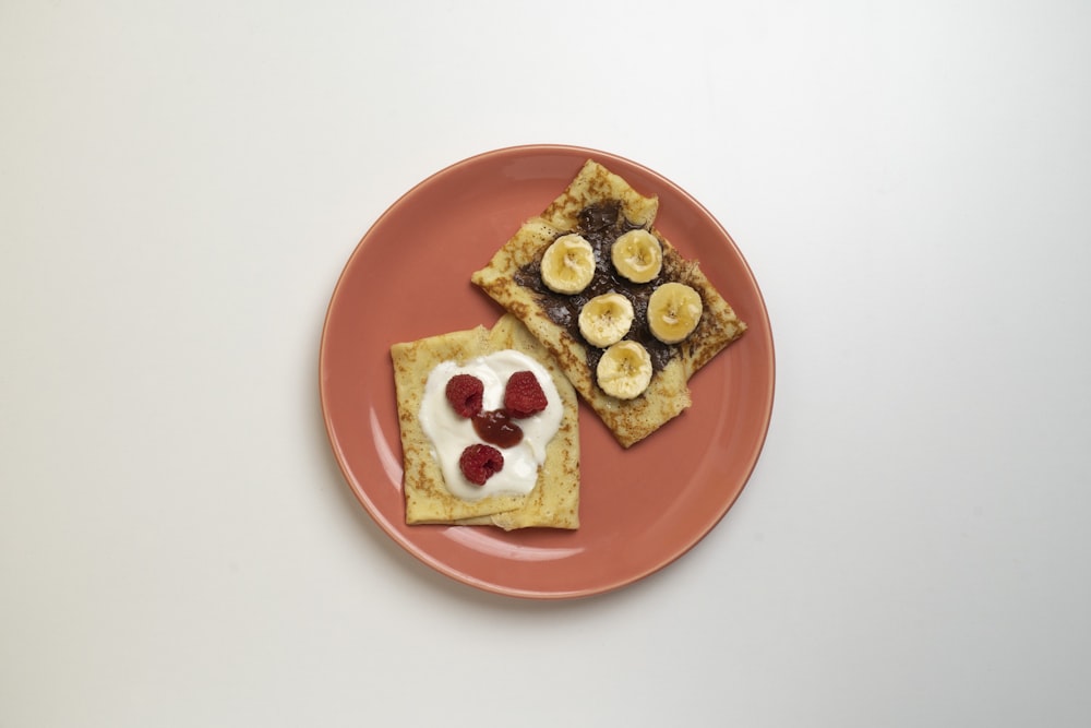 a pink plate topped with crackers and fruit