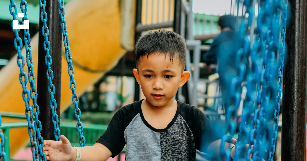 Foto Un niño parado en un columpio del patio de recreo – Imagen Persona ...
