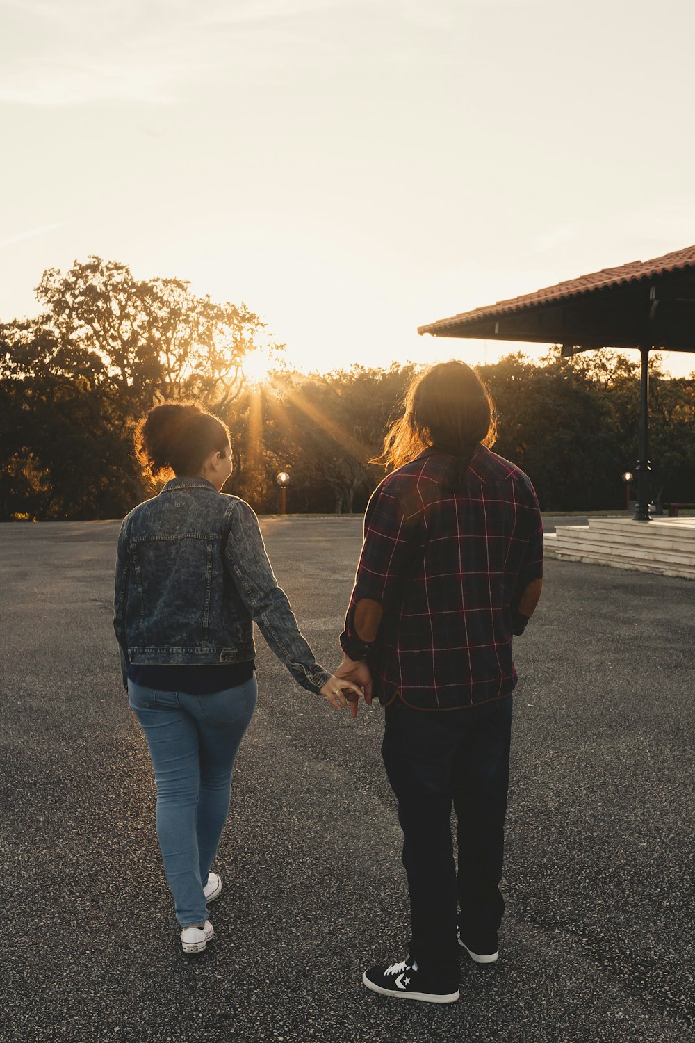 a man and a woman holding hands while walking across a parking lot