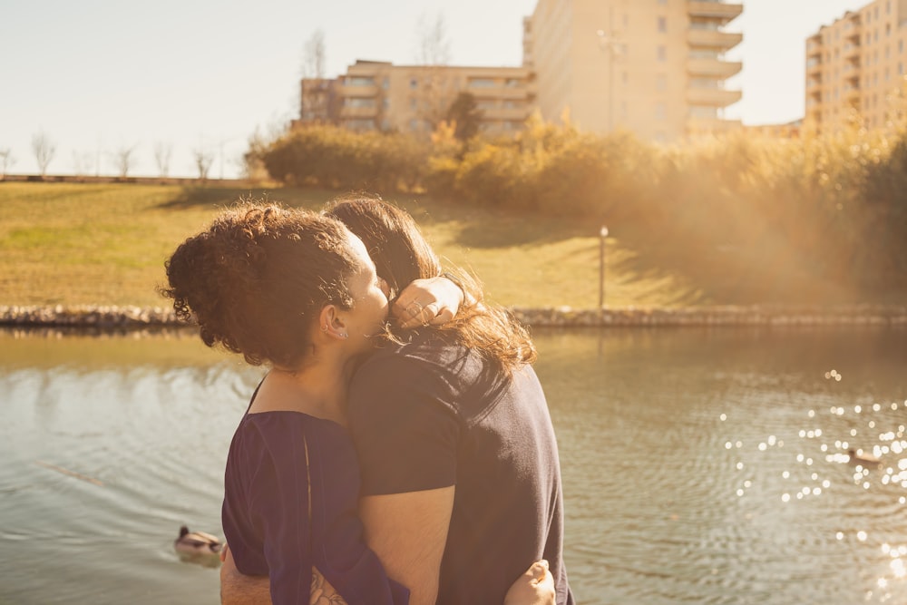 a couple of people that are standing in front of a body of water