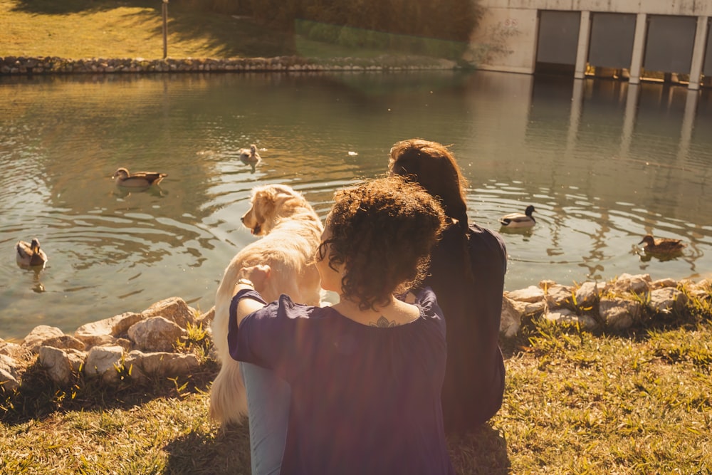 a couple of people that are sitting by a pond