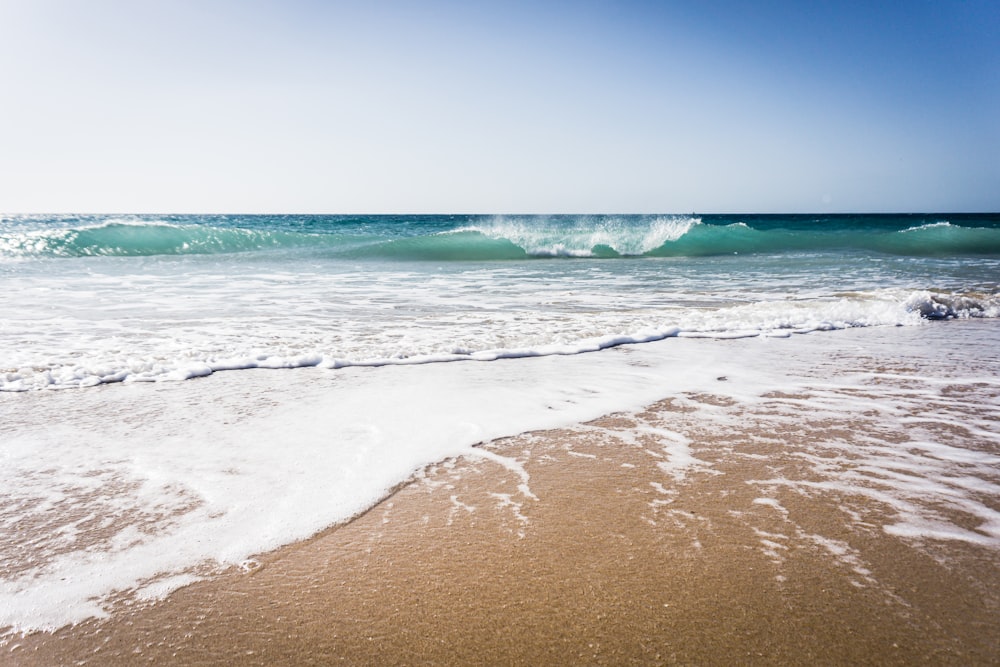 Ein Strand mit einer Welle, die ans Ufer kommt