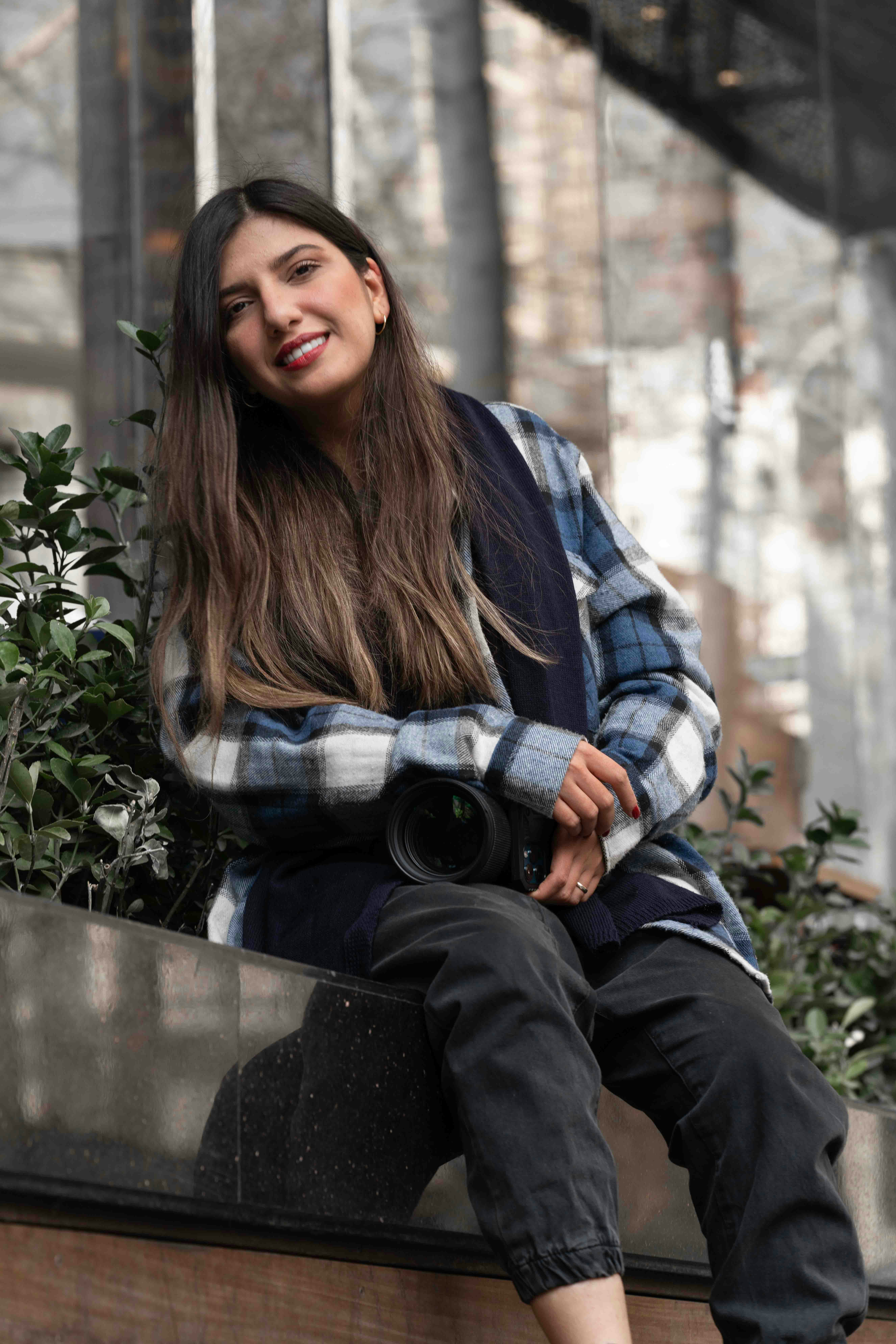 a woman sitting on a ledge with a camera