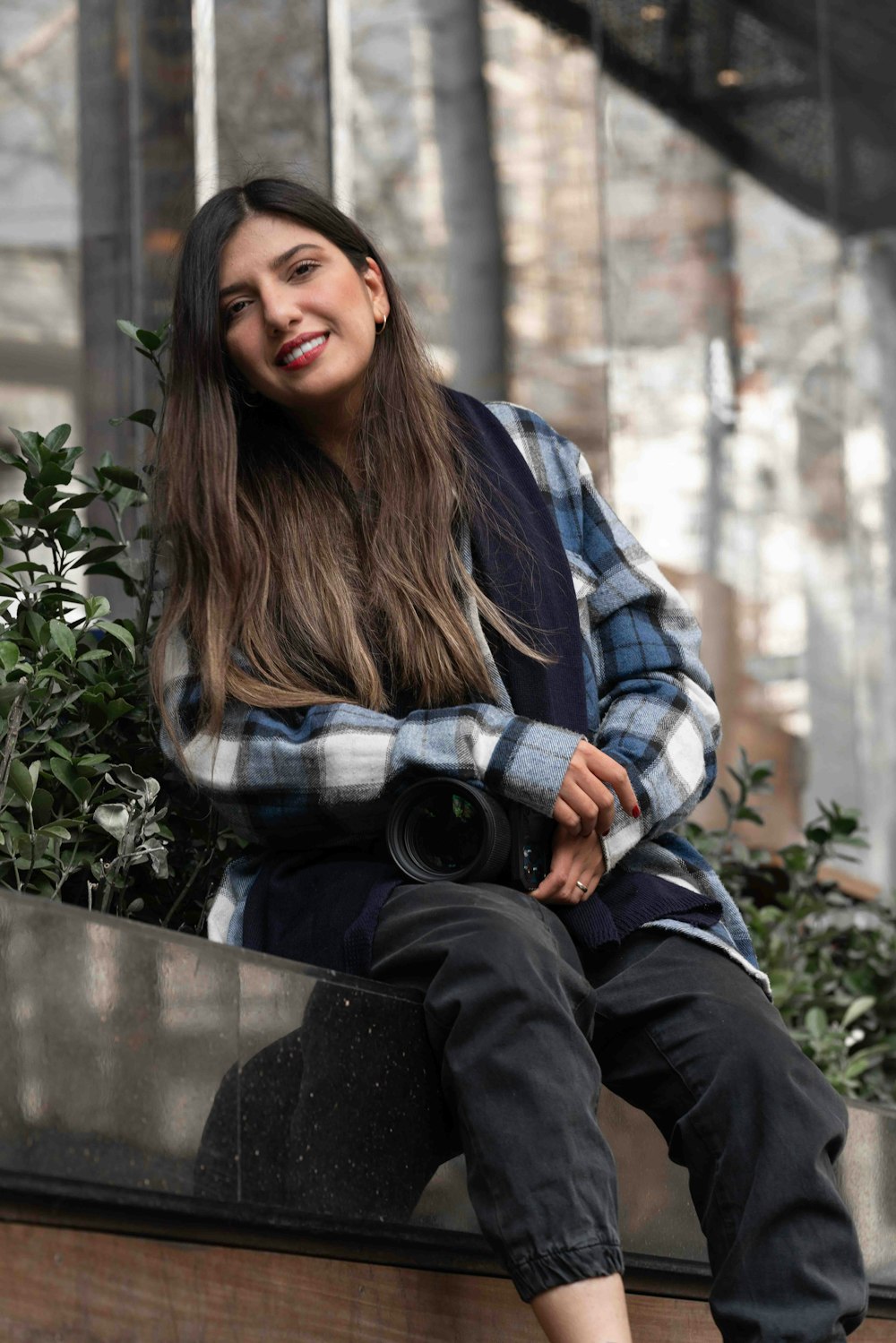 a woman sitting on a ledge with a camera