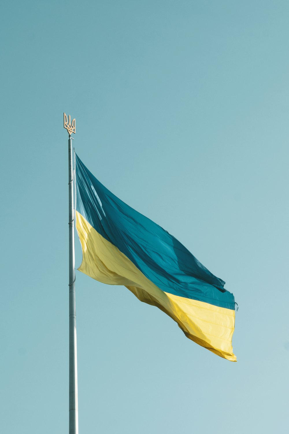 a flag flying in the wind with a blue sky in the background
