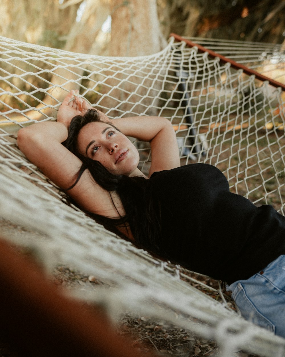 a woman laying in a hammock in the woods
