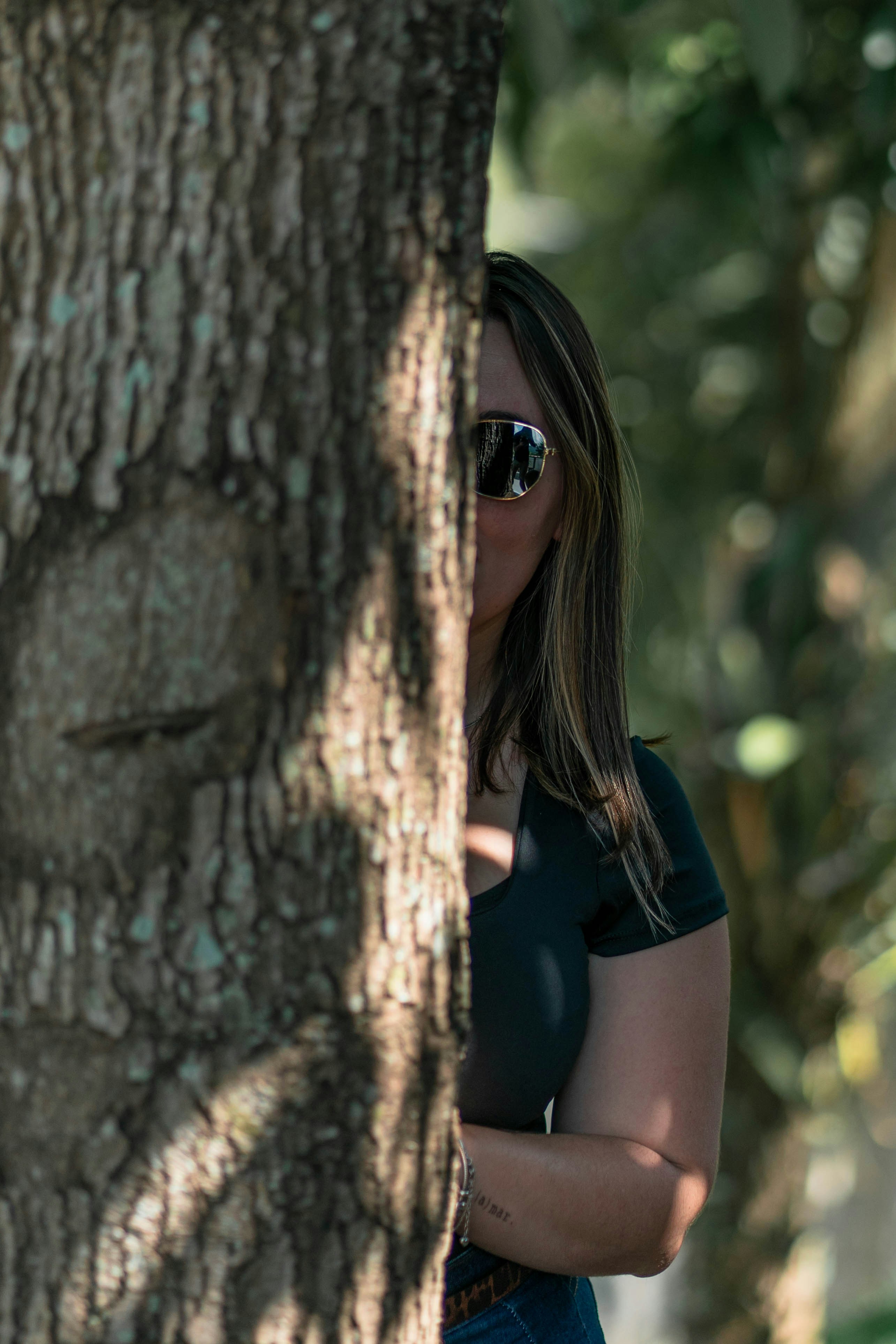 a woman standing next to a tree wearing sunglasses
