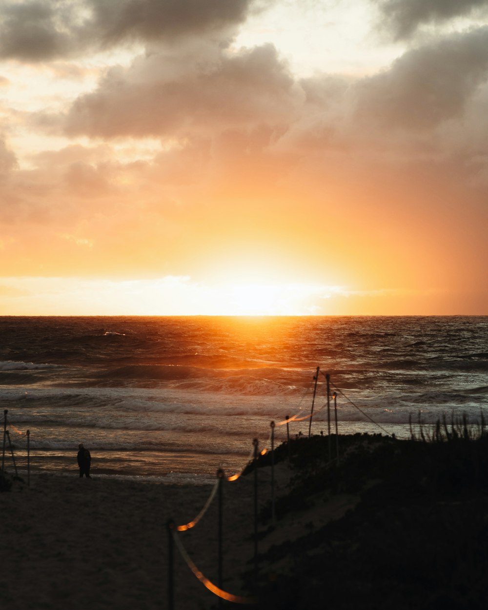 the sun is setting over the ocean on the beach