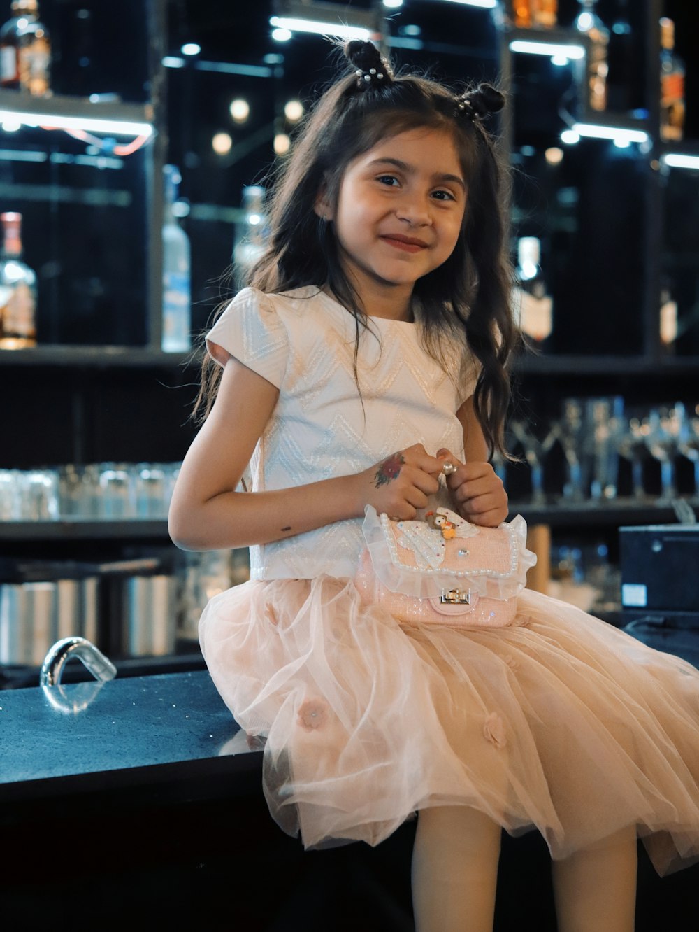 a little girl sitting on a counter holding a purse