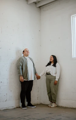 Smiling partners exchanging contract documents in a bright, minimalistic room.