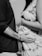 A close-up, black-and-white image features a pregnant person gently resting their hand on their belly. An individual standing opposite them places their hand on the belly as well, showcasing a moment of connection and anticipation.