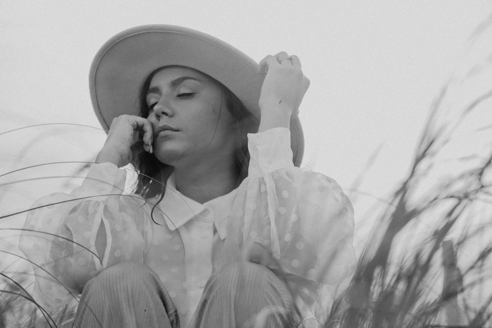 a woman in a hat sitting in tall grass