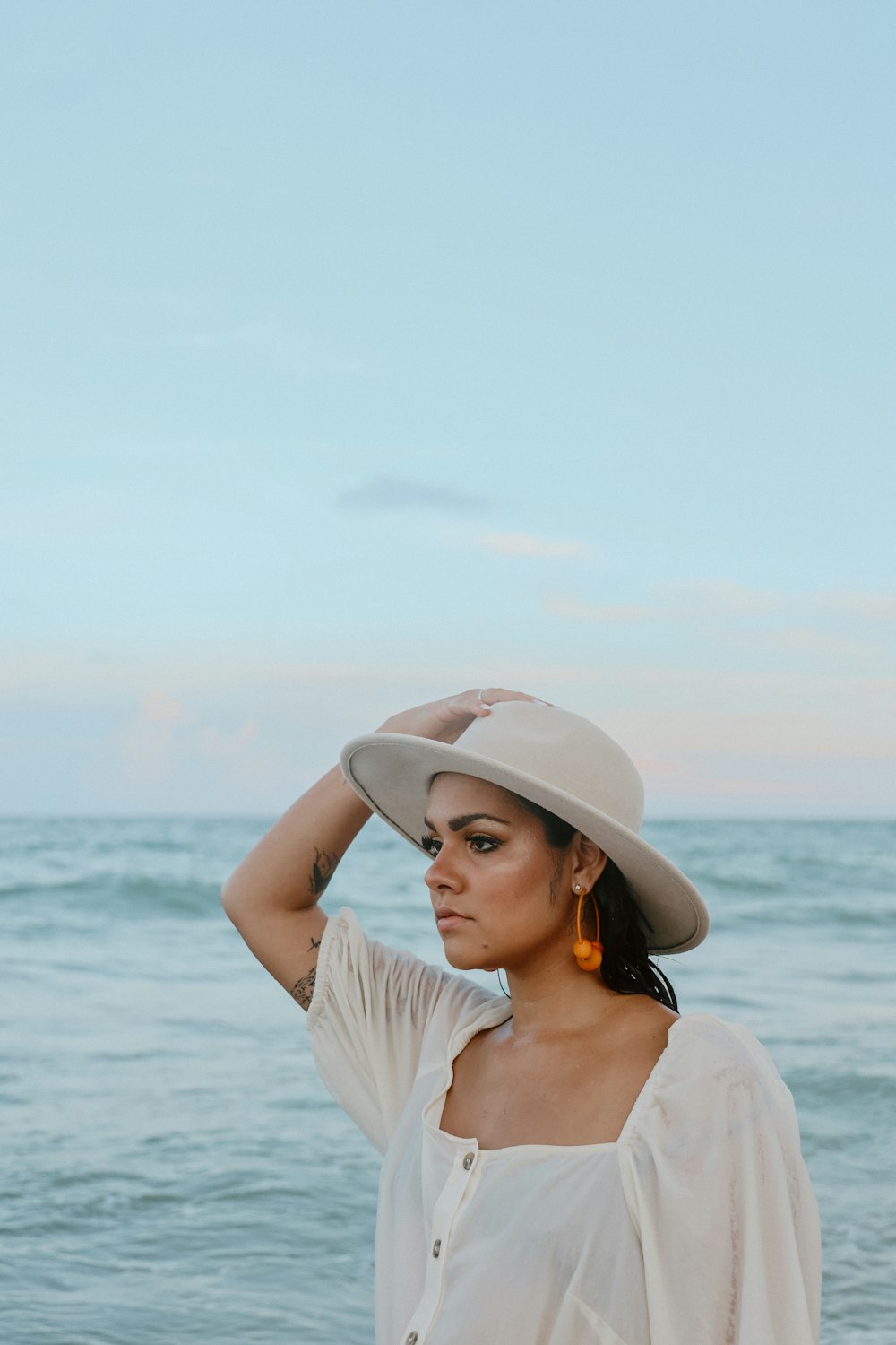 해변에 서 있는 모자를 쓴 여자