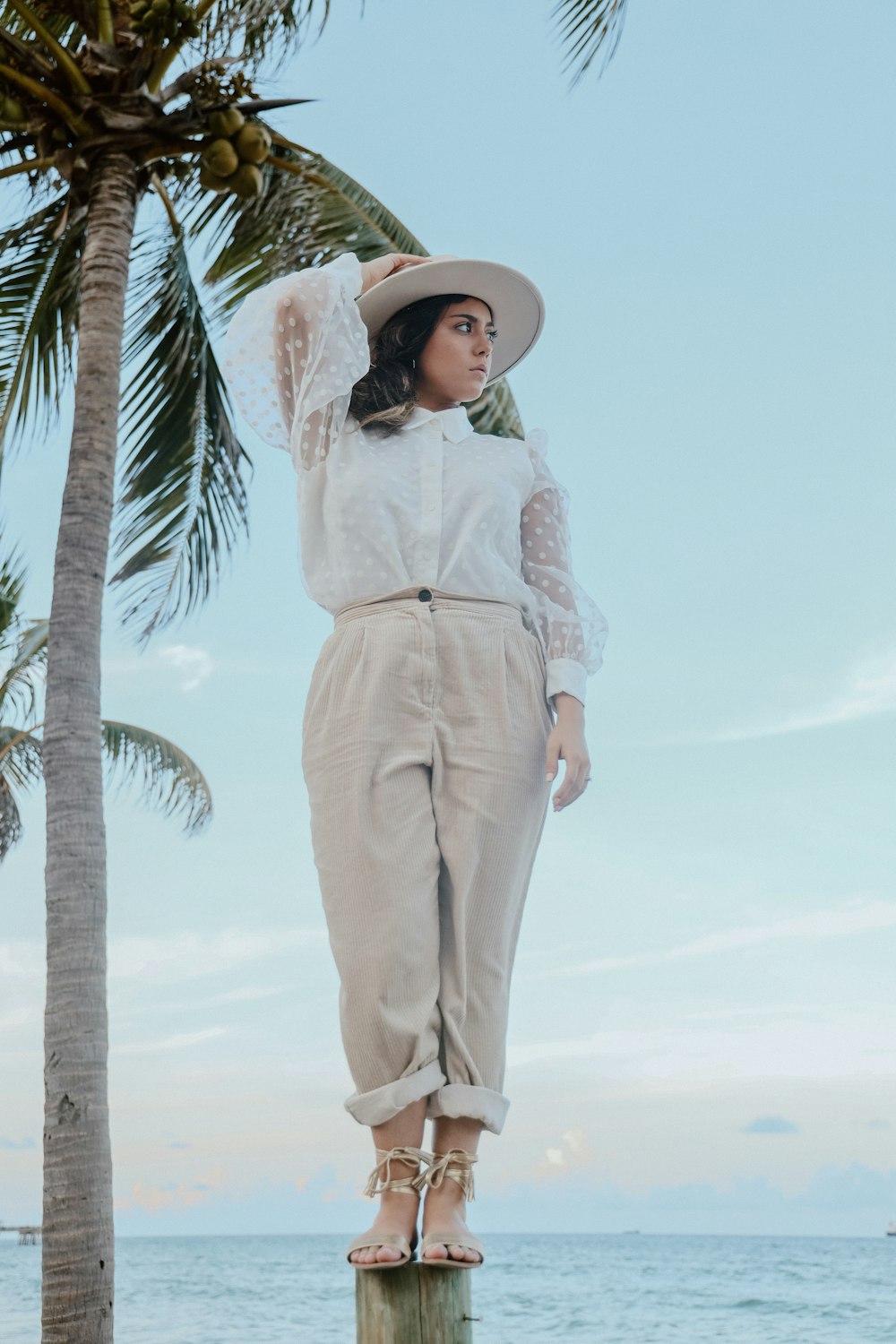 a woman standing on top of a wooden pole near the ocean