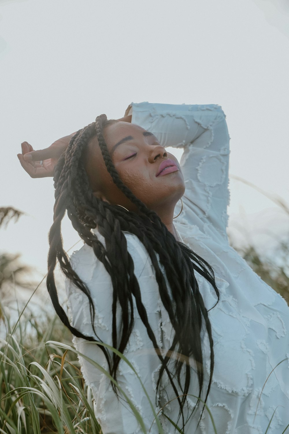 a woman with dreadlocks standing in tall grass