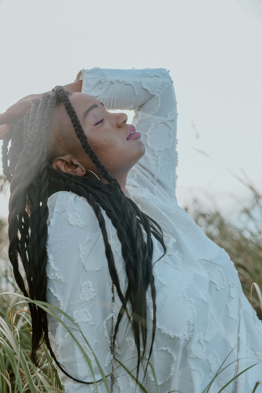 a woman with long hair standing in tall grass