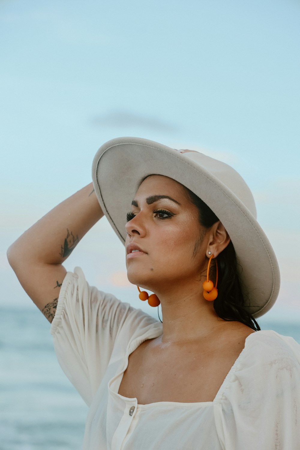 a woman wearing a hat standing near the ocean