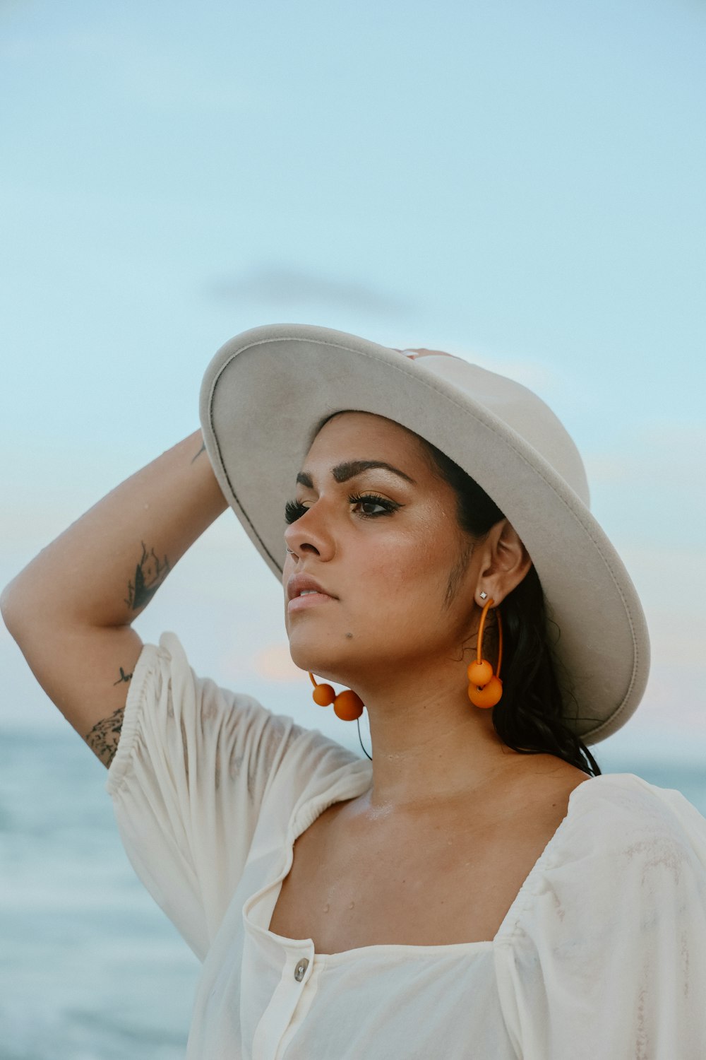 a woman wearing a white hat and orange earrings