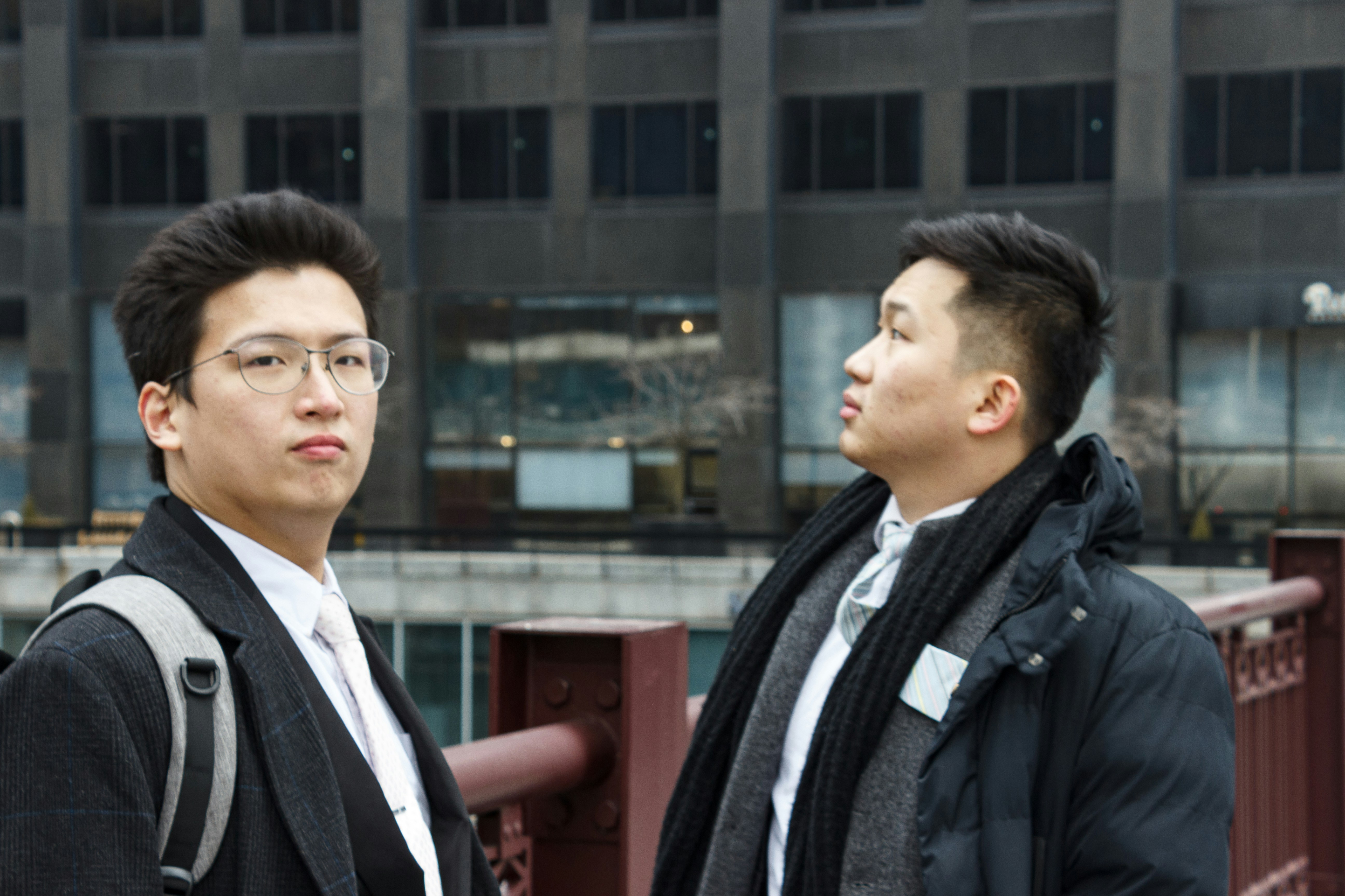 two men standing next to each other in front of a building