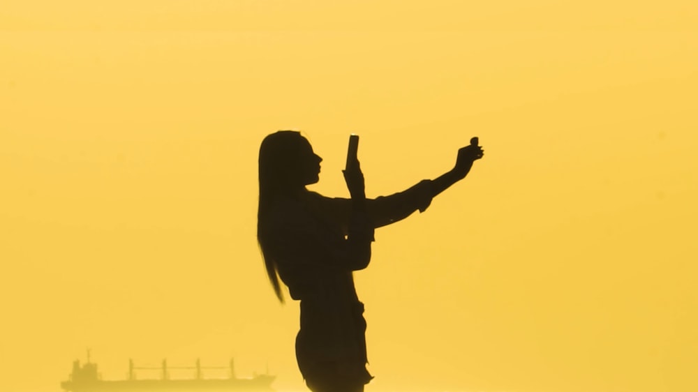 a silhouette of a woman holding a cell phone