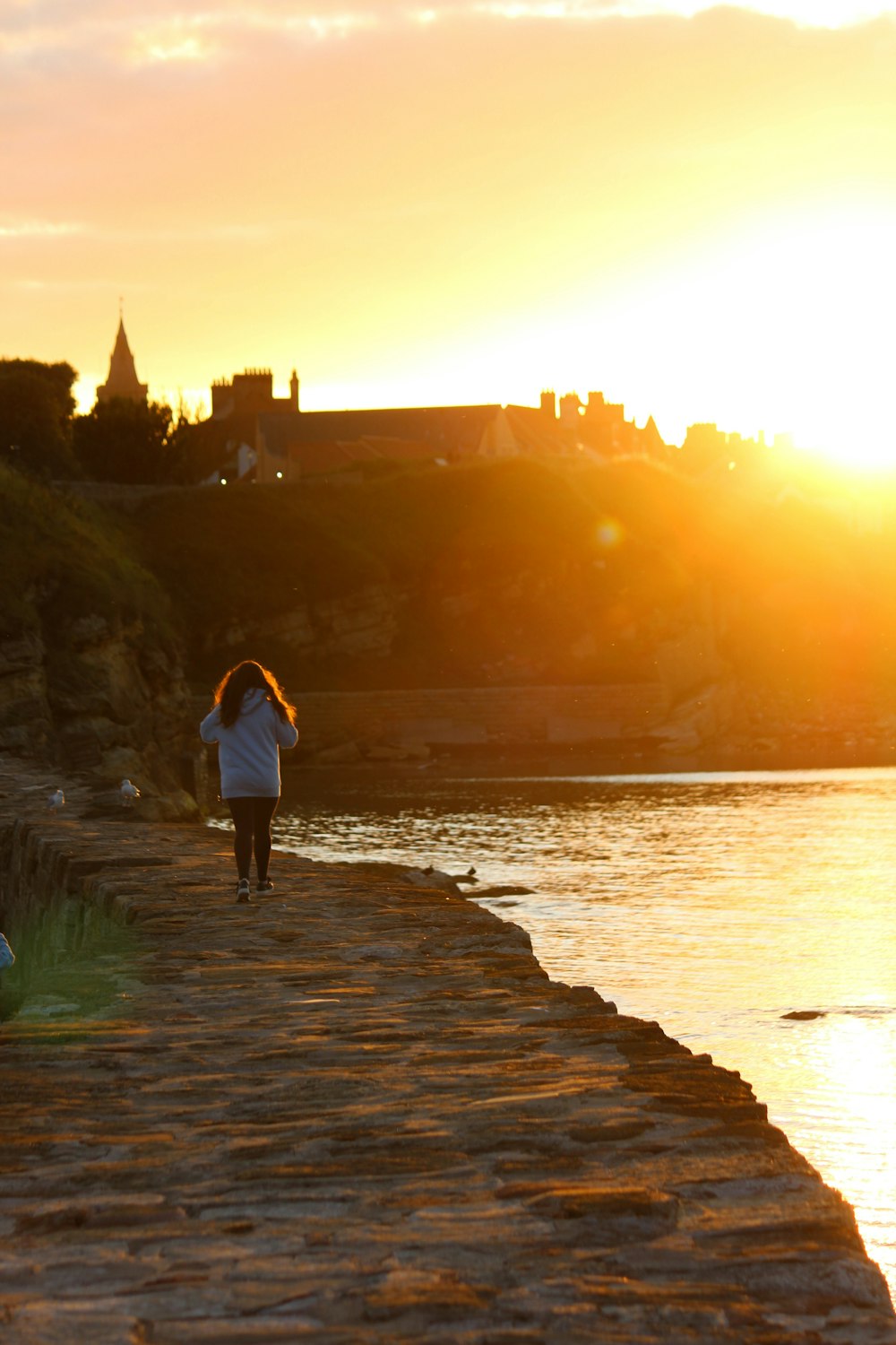 a woman is walking along a path near a body of water