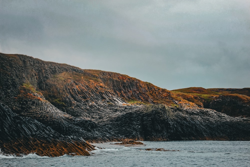 a large body of water sitting next to a lush green hillside