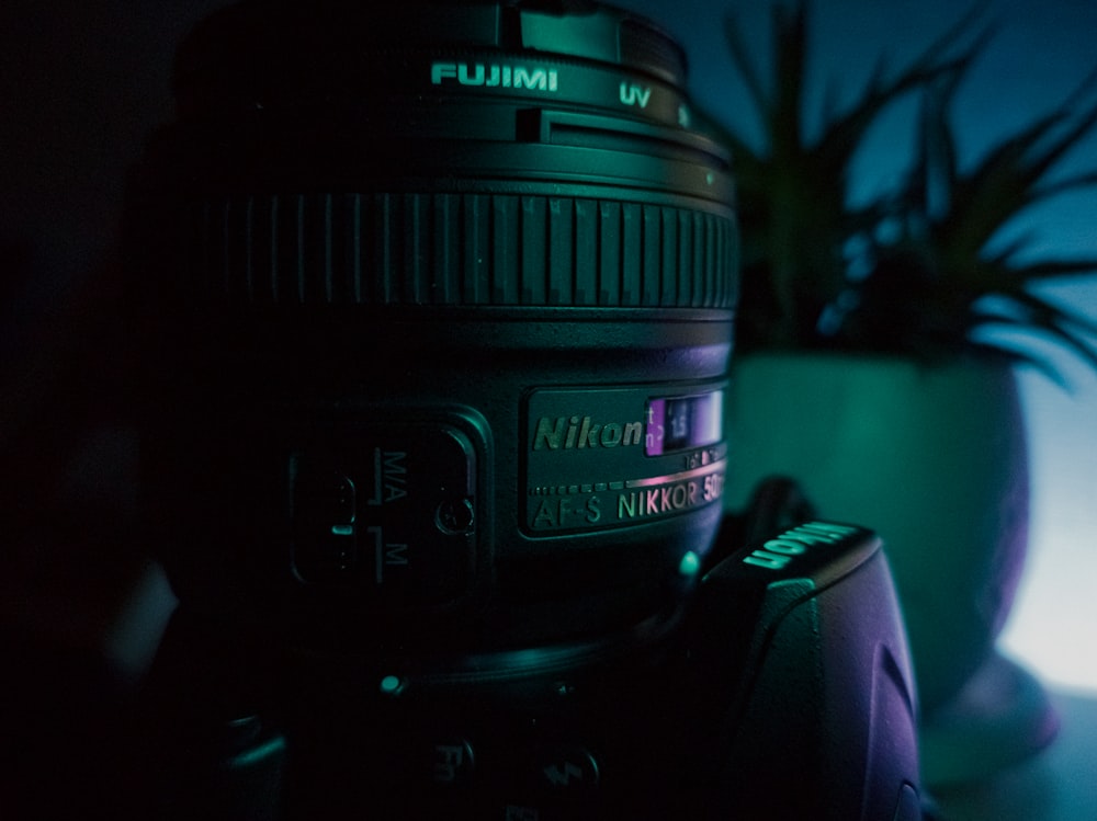 a close up of a camera with a plant in the background