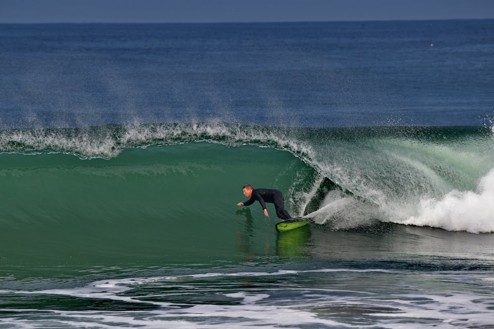 a man riding a wave on top of a green surfboard