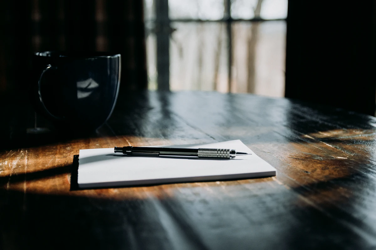 Notebook dan pena di atas meja kayu untuk mencatat ide brainstorming konten kreator yang dibantu AI sebelum dieksekusi