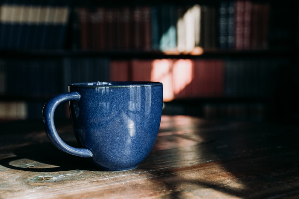 a blue coffee cup sitting on top of a wooden table