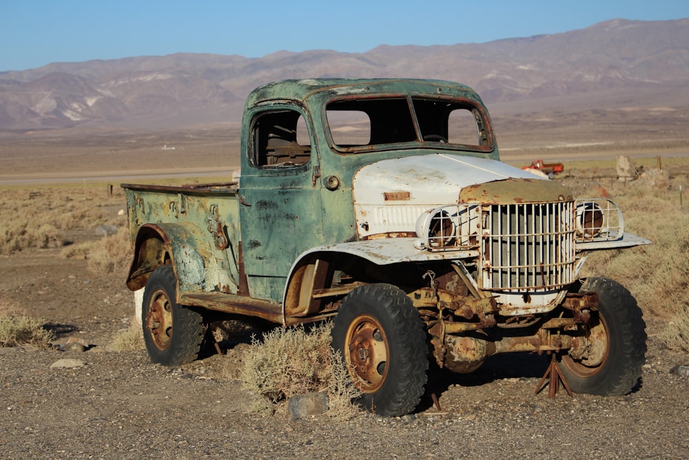an old truck sitting in the middle of the desert