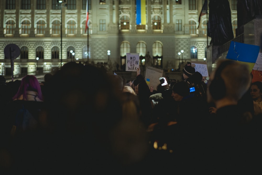 a crowd of people holding signs in front of a building
