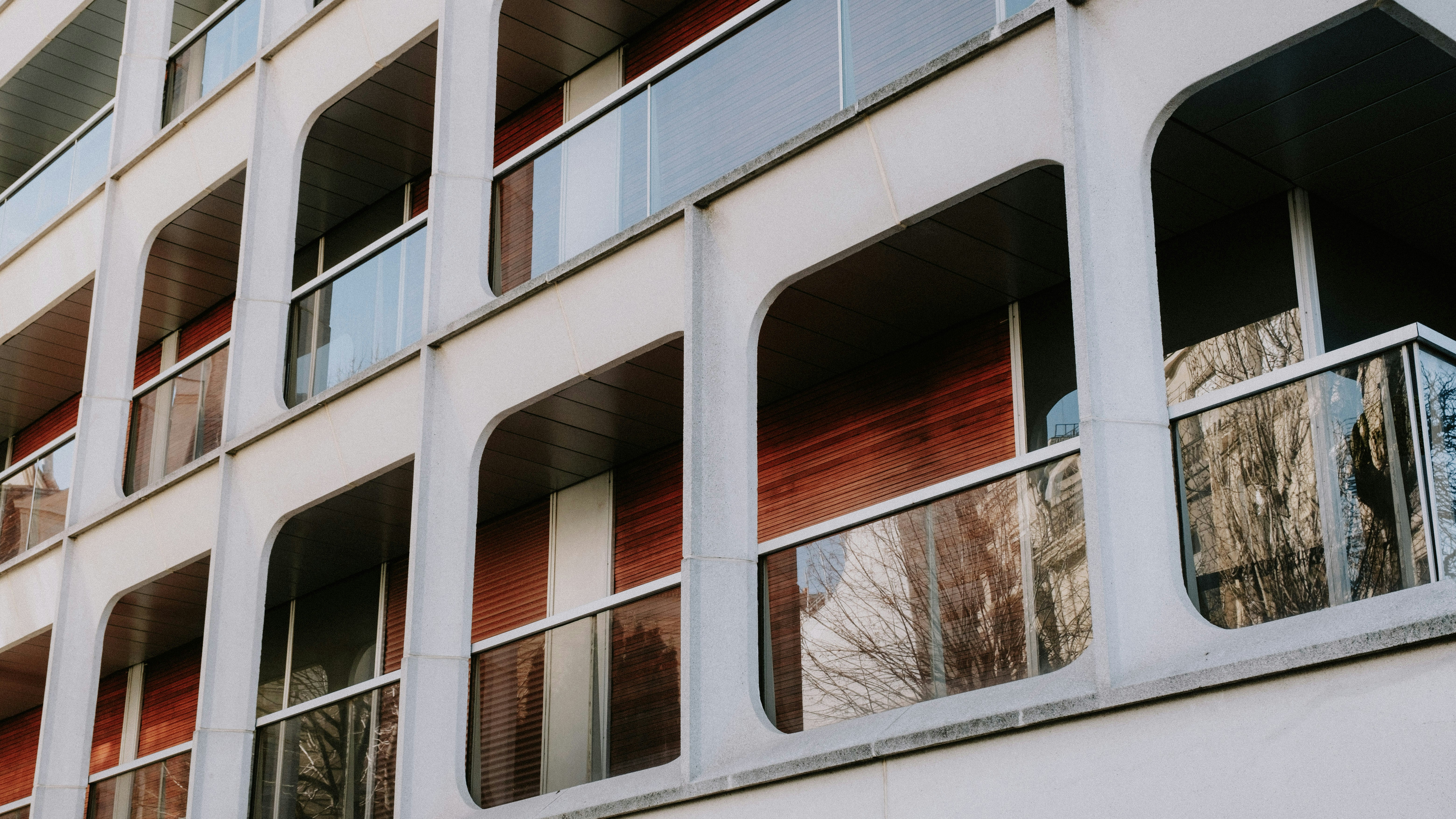 A modern apartment building exterior with glass windows showing an amenity space - indoor pool apartments