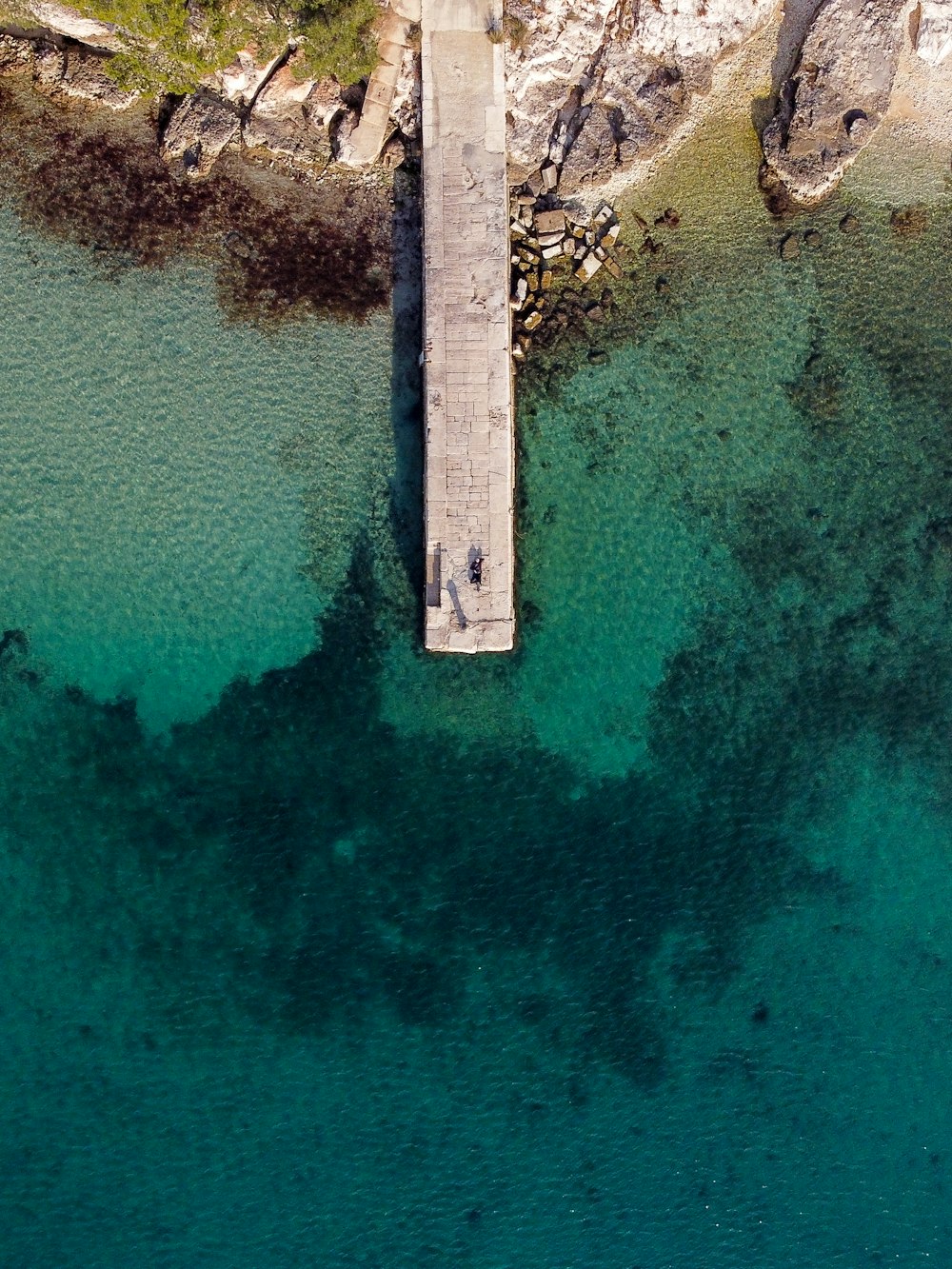 an aerial view of a pier in the middle of a body of water