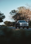 a black truck driving down a street next to trees