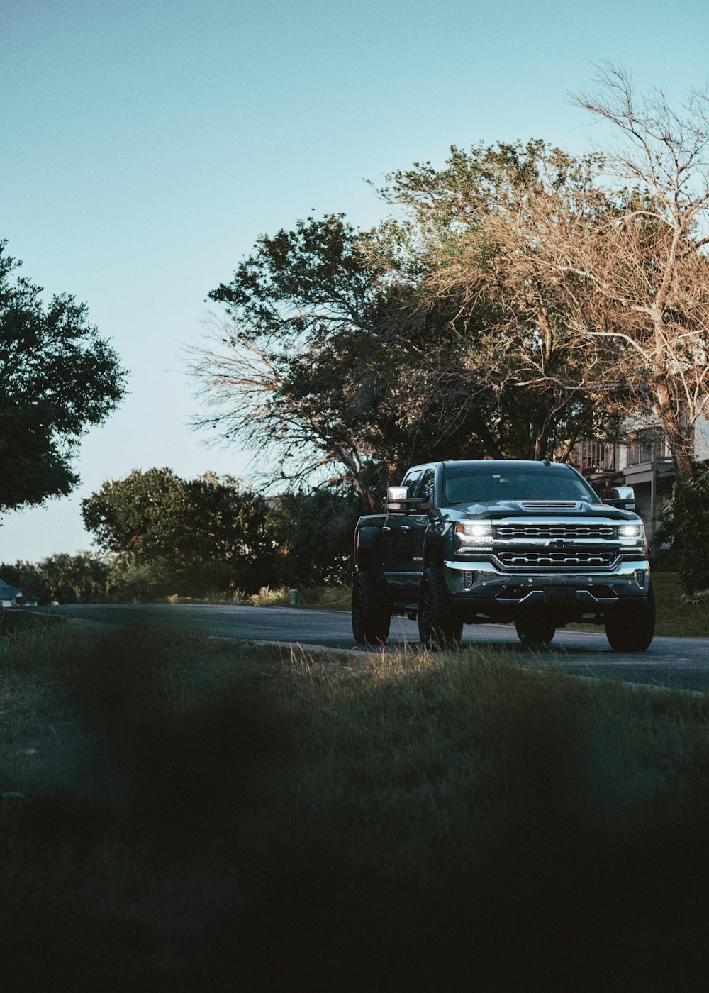 a black truck driving down a street next to trees