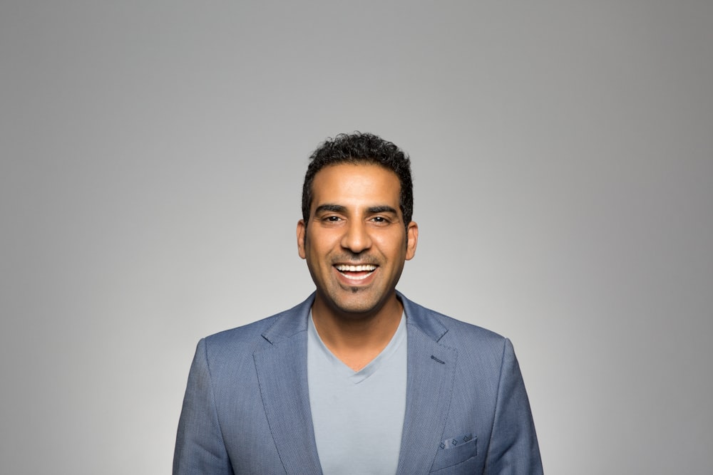 a man in a blue suit smiling for the camera