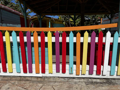 A variety of colorful fence panel covers displayed outdoors on different fence types.
