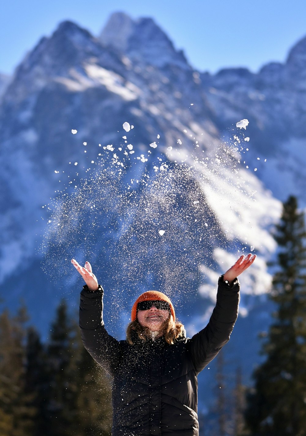 a woman is throwing snow in the air