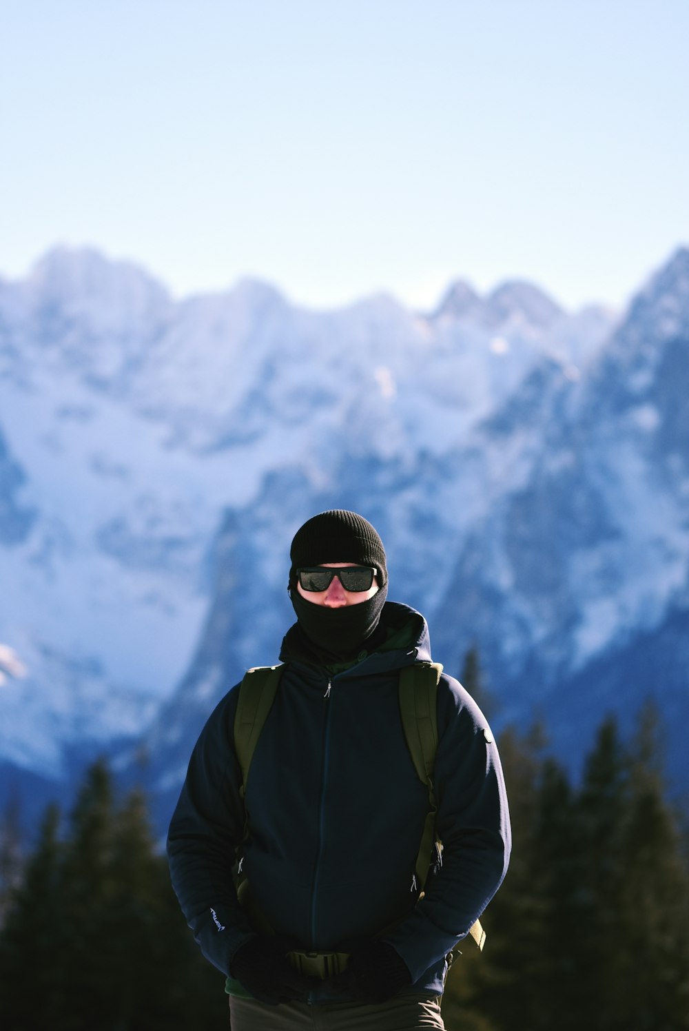 um homem de pé na frente de uma montanha coberta de neve